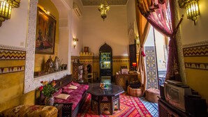 A traditional Moroccan interior with a sofa, a coffee table, and a television.