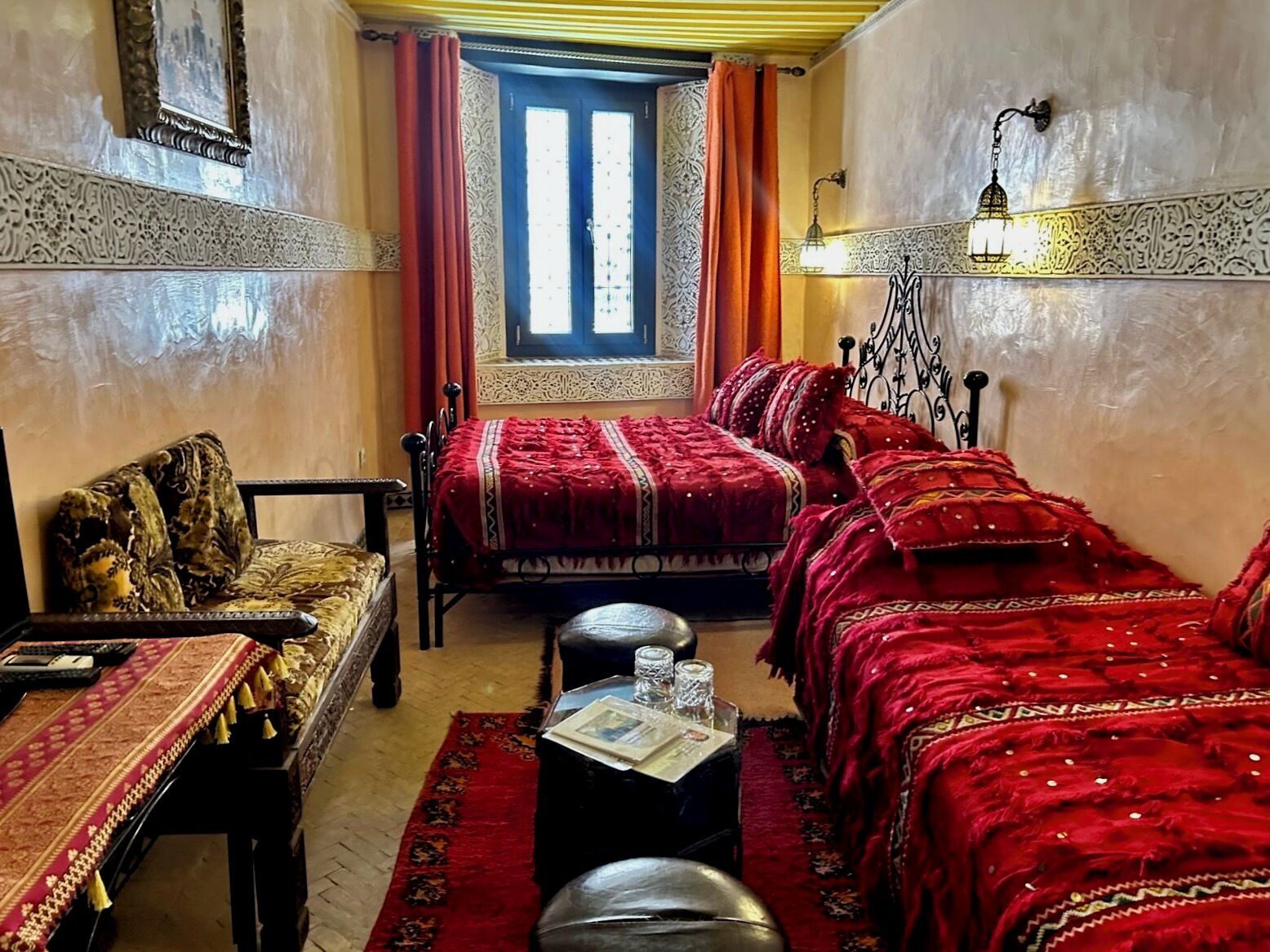Quarto tradicional com cama, sofá, mesa e janela com cortinas.