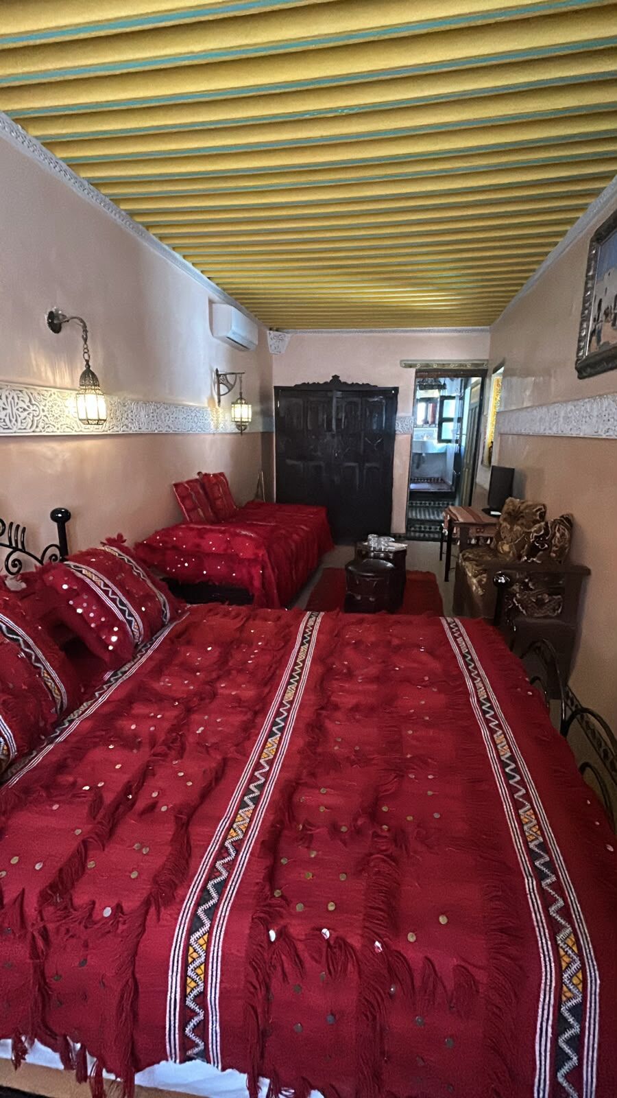 Quarto com uma cama grande, uma mesa pequena, uma cadeira e uma porta.