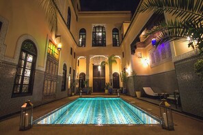 A pool area with tiled walls, a pool, and lounge chairs.