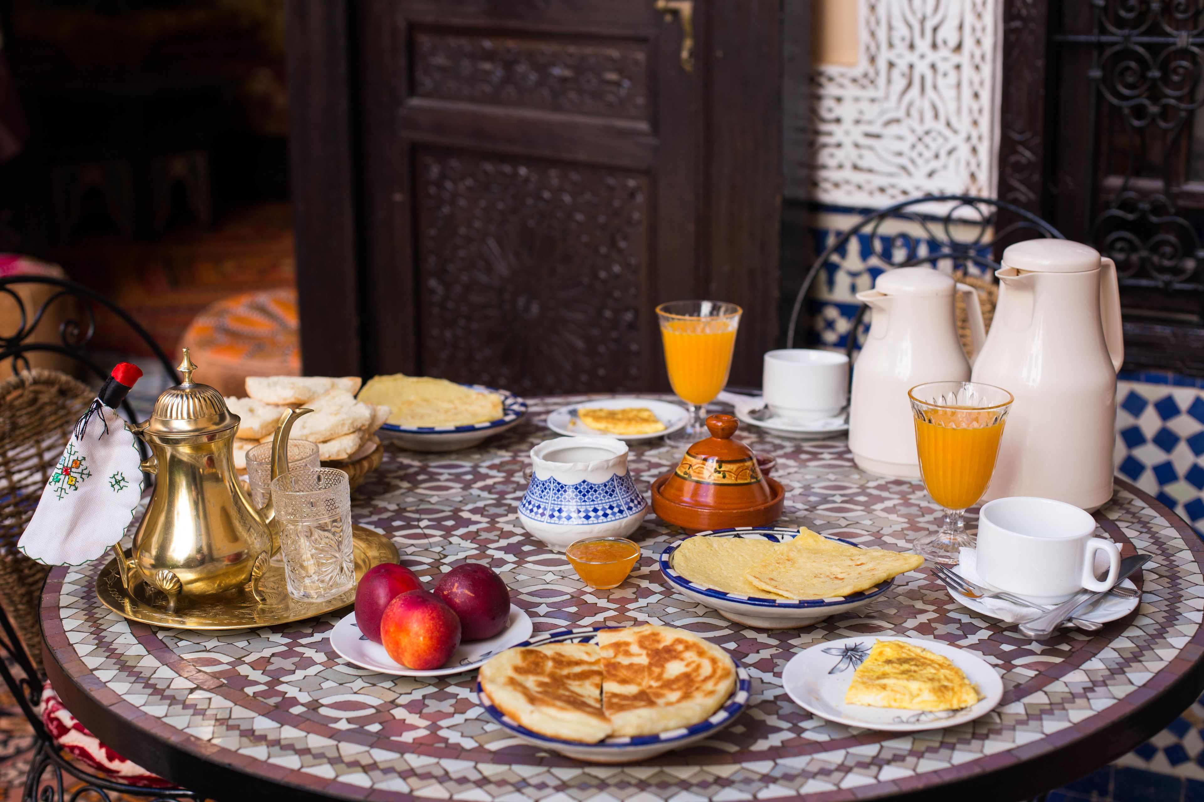 Une table de petit-déjeuner avec divers plats, notamment des fruits, des viennoiseries et des boissons.