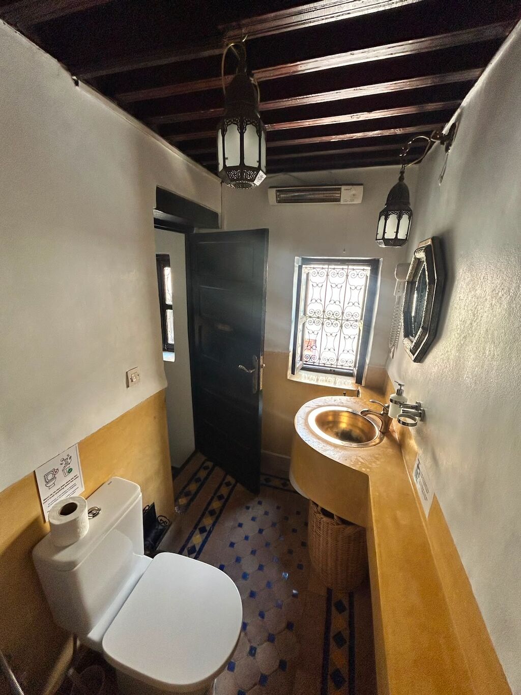 A narrow bathroom with a toilet, sink, and window.