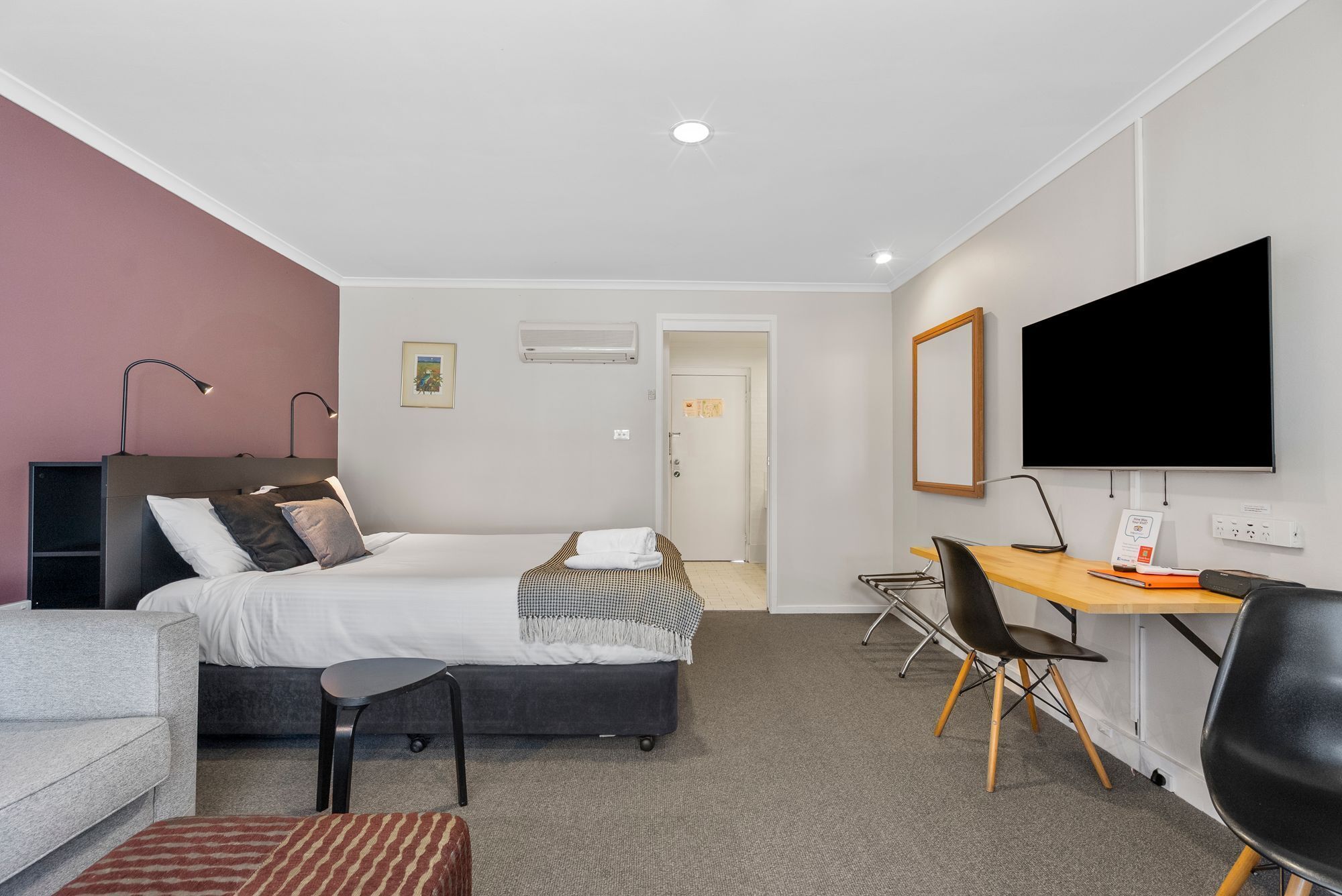 Et moderne hotelværelse med seng, skrivebord, stol og fjernsyn.