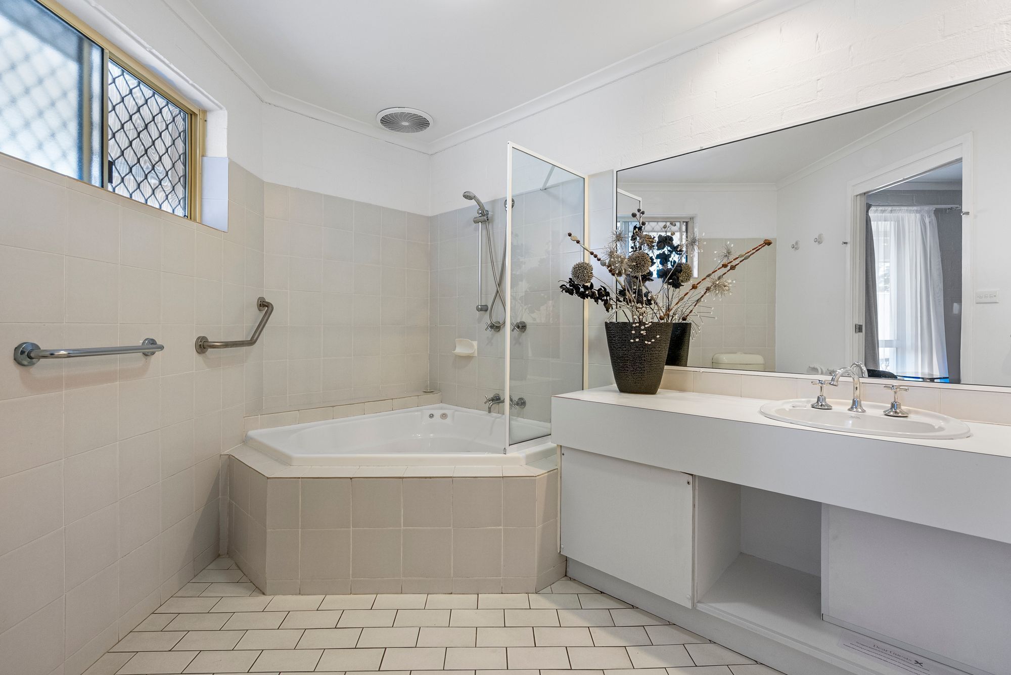 A modern bathroom with a bathtub, shower, and two sinks.
