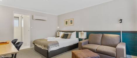 Une chambre d’hôtel avec un lit, un canapé, une petite table et une chaise.