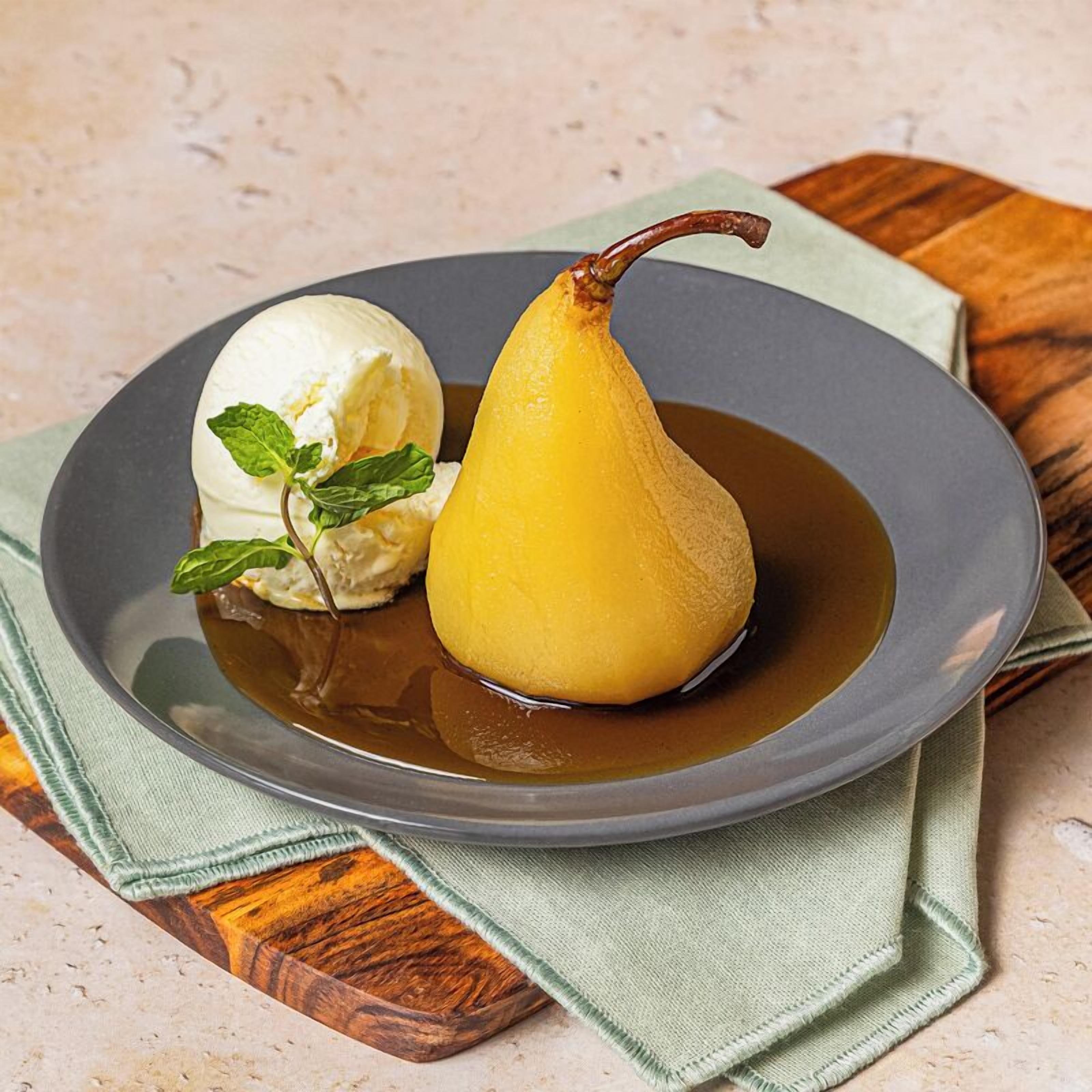 A dessert plate with a pear and a scoop of ice cream, accompanied by a mint leaf garnish.