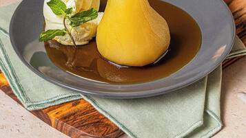 A dessert plate with a pear and a scoop of ice cream, accompanied by a mint leaf garnish.