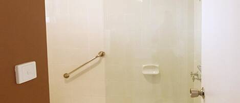 Un baño con ducha de vidrio, una bañera blanca y un perchero para toallas.