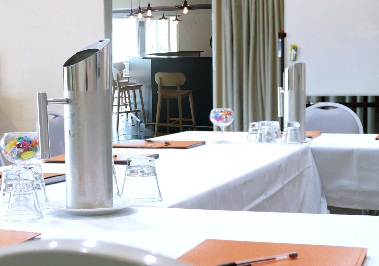 A conference room with tables set for a meeting, a water pitcher, and a glass pitcher on the table.