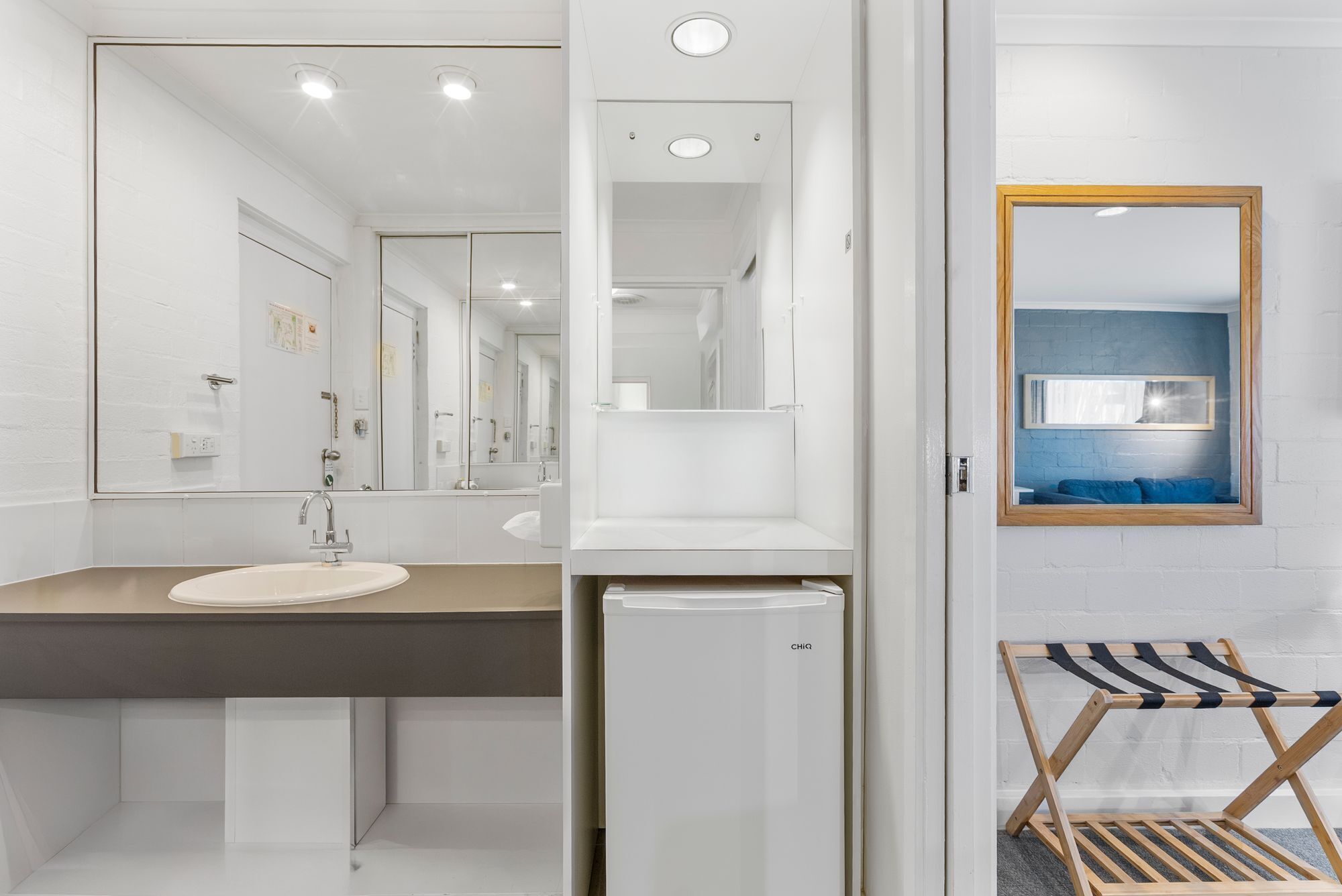 Un baño moderno con un espejo grande, un lavabo y un inodoro pequeño.