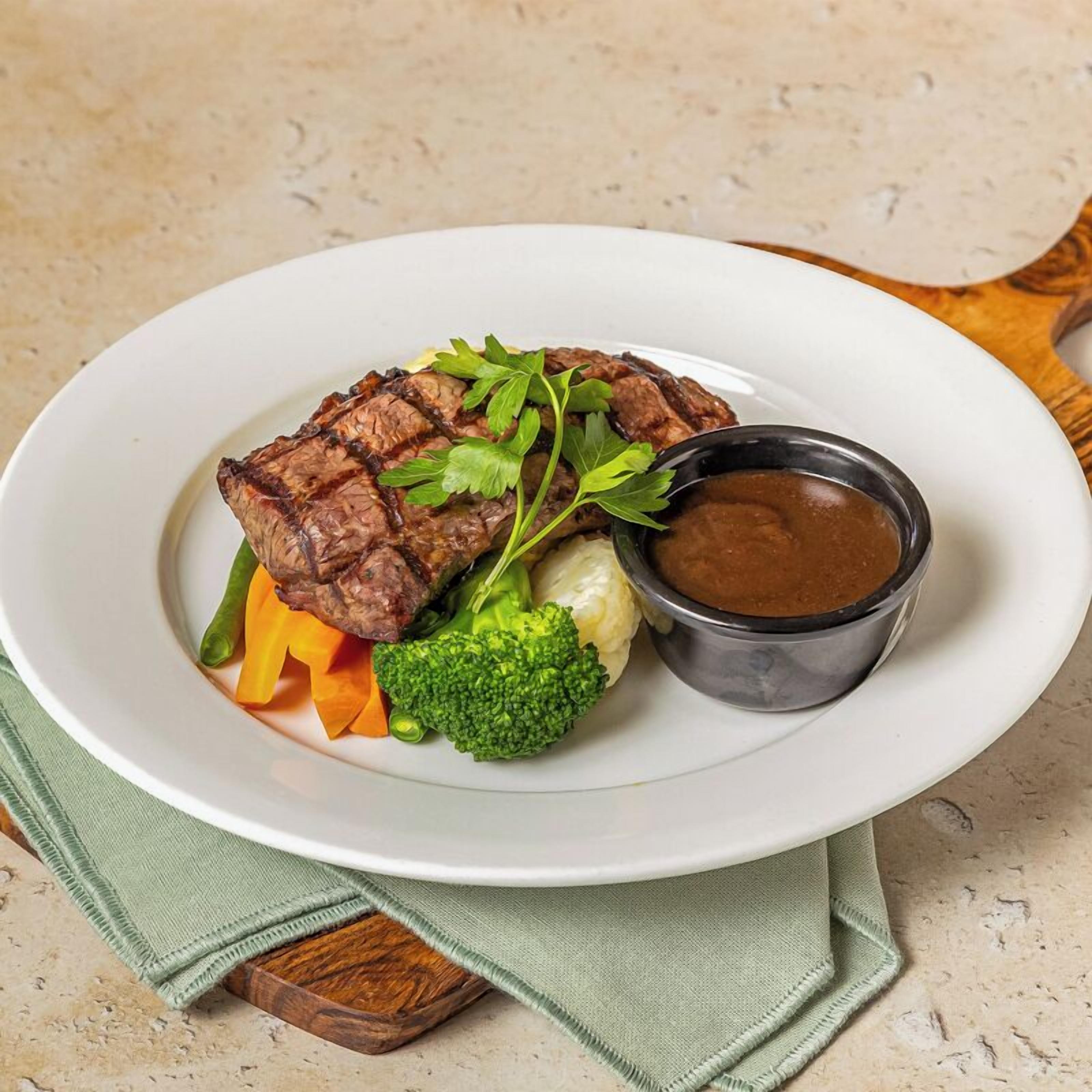 A plate with steak, vegetables, and a sauce.