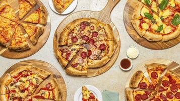 A variety of pizzas on wooden boards.