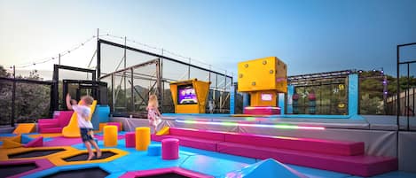 Un'area giochi al coperto con strutture imbottite colorate e un trampolino.