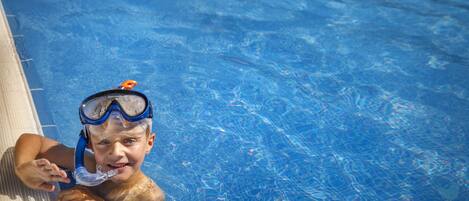 Ein Kind in einem Schwimmbecken mit klarem, blauem Wasser.