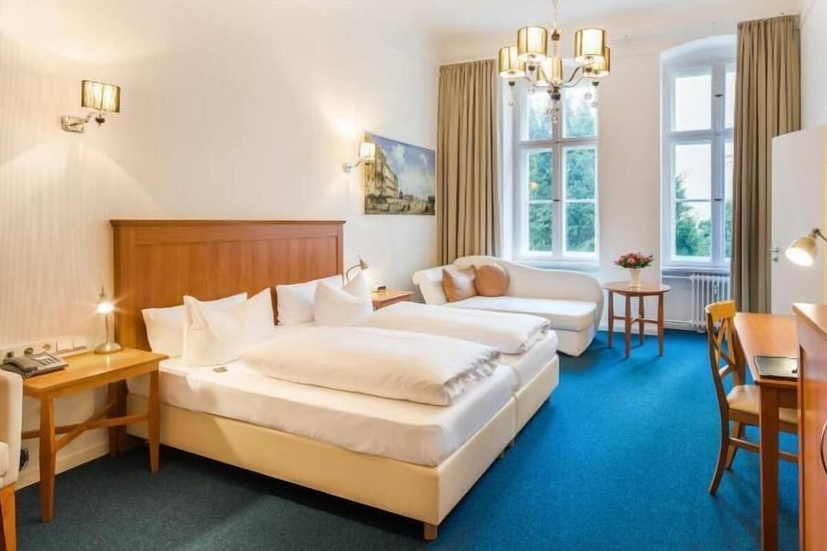 Habitación de hotel con dos camas, un escritorio, una silla, un televisor y una ventana con cortinas.