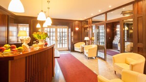 A reception area with a wooden counter, a red carpet, and yellow armchairs. - Hotel Brandies Berlin (Berlin)
