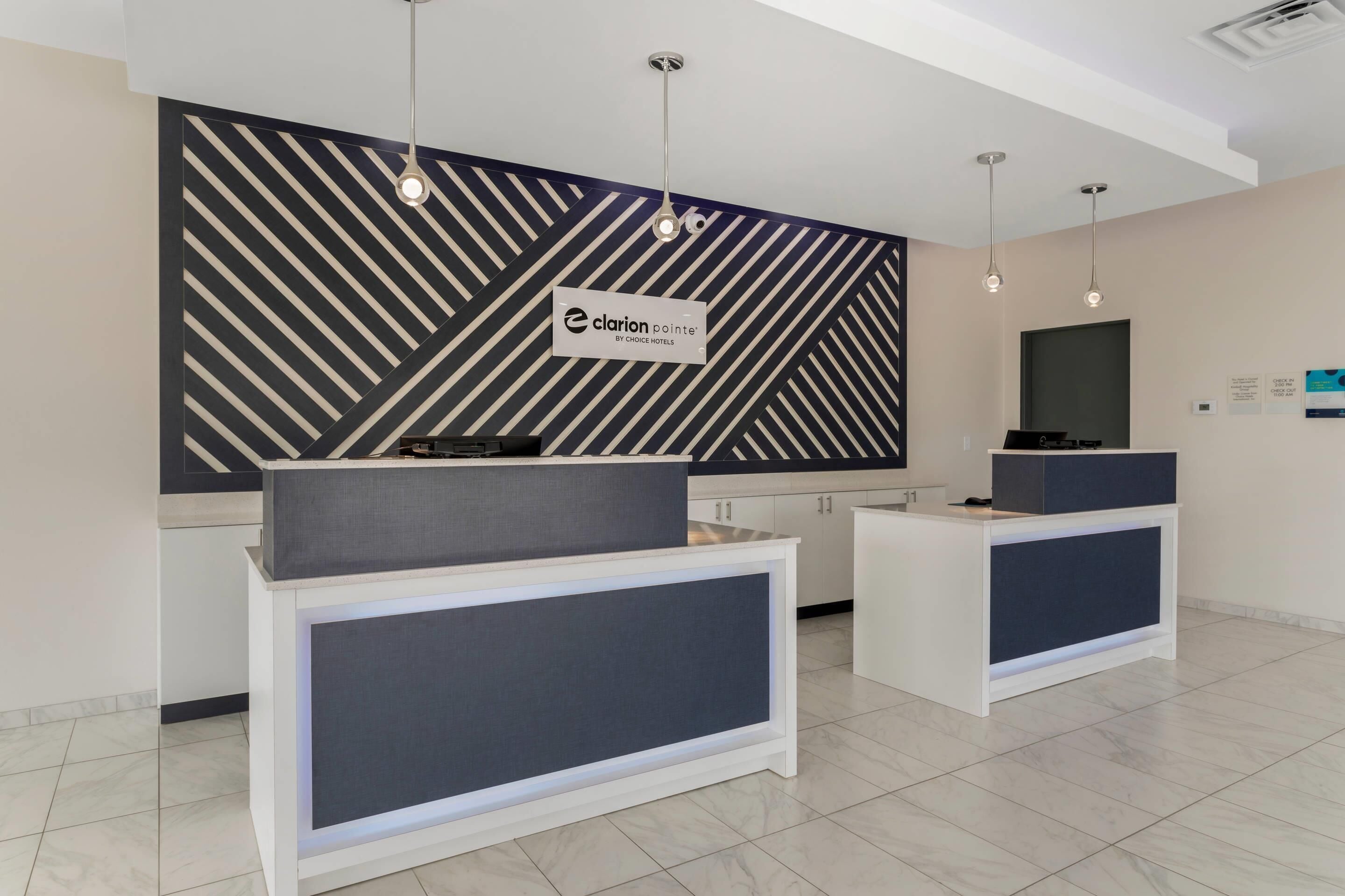 A reception area with a modern design, featuring a geometric patterned wall, a reception desk, and pendant lighting.