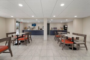 A clean, well-lit dining area with modern furniture and a visible counter in the background.