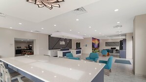 Eine moderne Hotelhalle mit einer zentralen Insellounge, Sitzgelegenheiten und einer Rezeption.