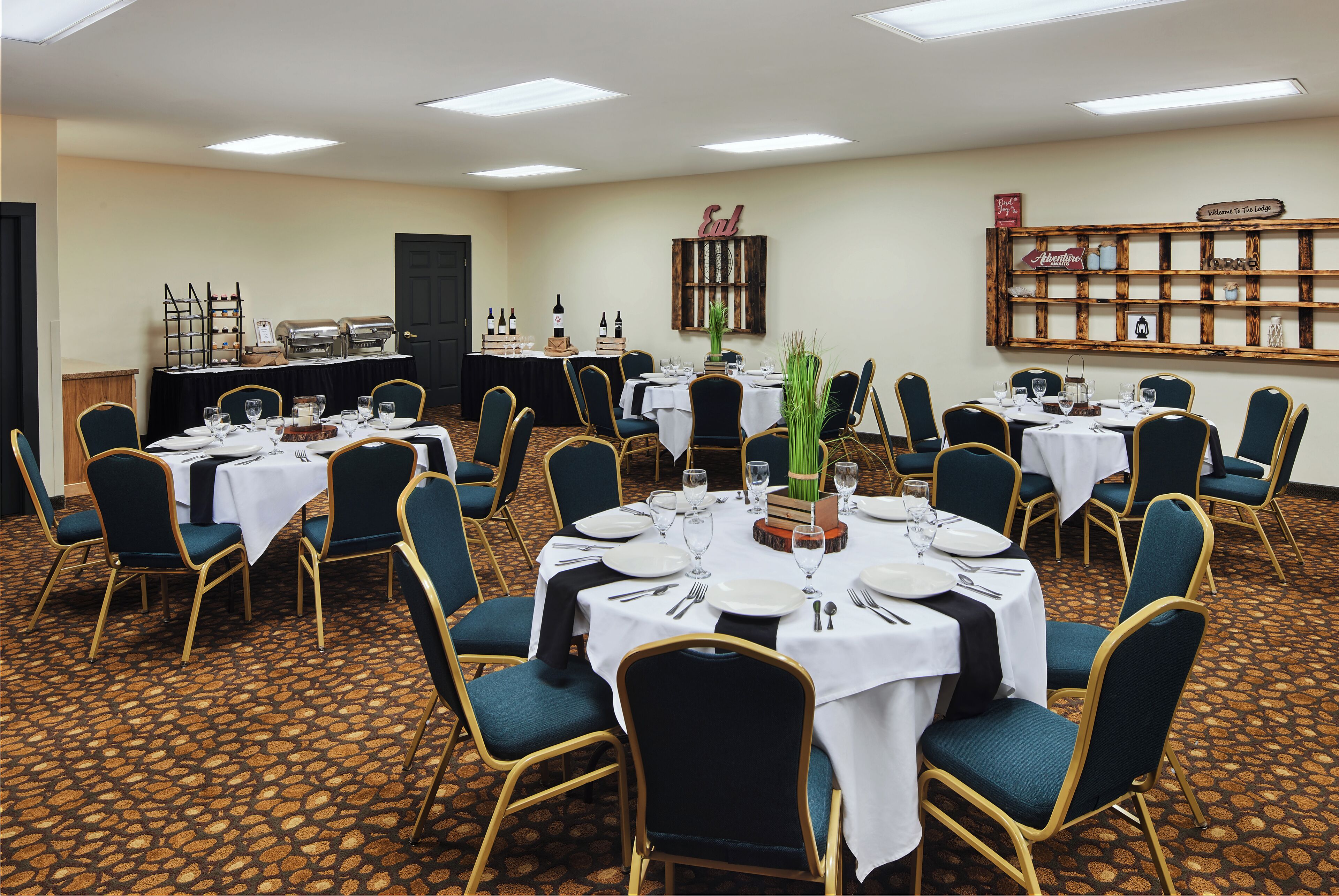 Un salón de conferencias con varias mesas dispuestas para comer, equipado con sillas, mesas y una zona de bufé.