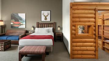 A hotel room with a bed, a wooden bench, a suitcase, a lamp, and a wooden wall structure.