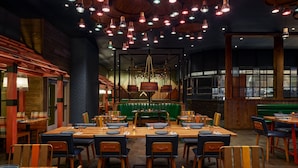 A restaurant with wooden tables and chairs, green booths, and hanging pendant lights. - Great Wolf Lodge Pocono Mountains, PA (Scotrun)