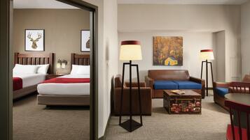 A hotel room with two beds, a sofa, a coffee table, and two floor lamps.