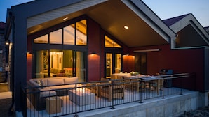 A modern house with a large glass window, a patio with outdoor furniture, and a barbecue grill. - Great Wolf Lodge Pocono Mountains, PA (Scotrun)