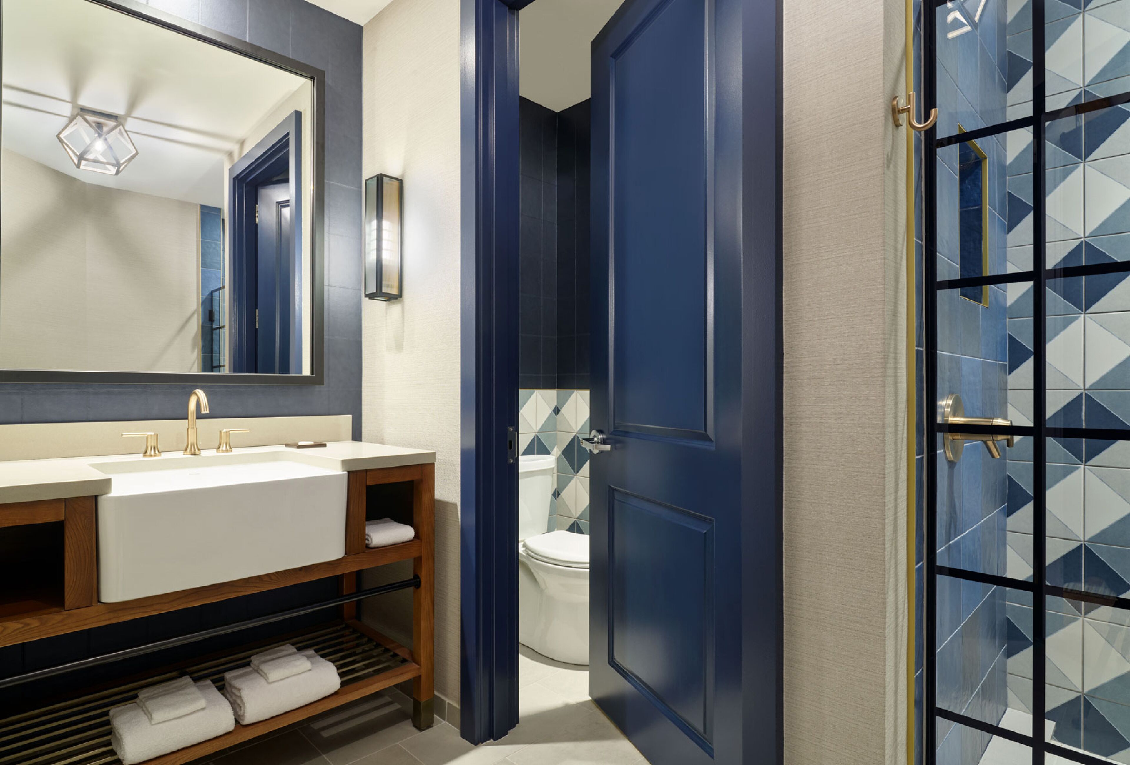 A modern bathroom with a large mirror, a sink, and a toilet.