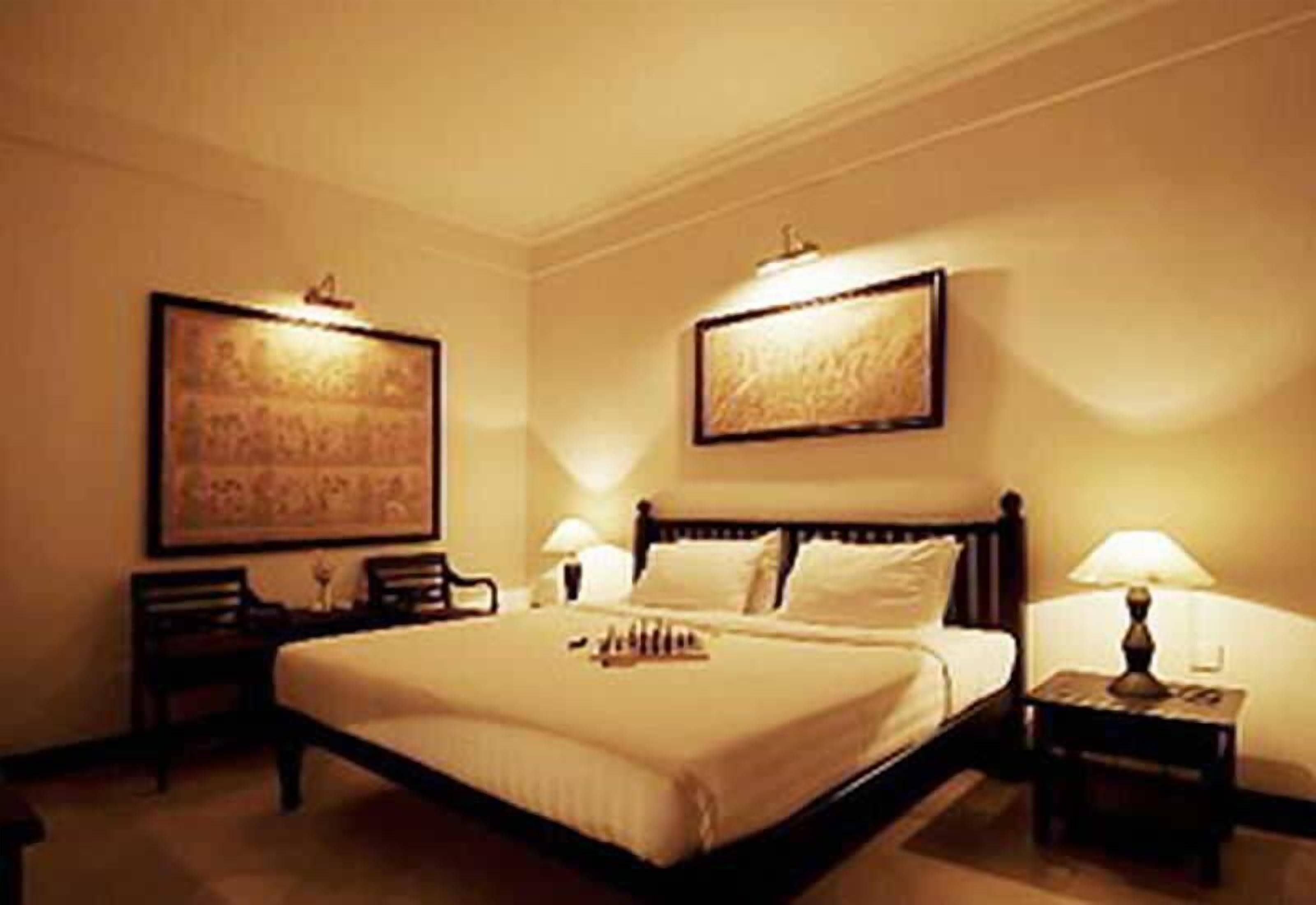 A hotel room with a large bed, two bedside tables, and two wall-mounted lamps.