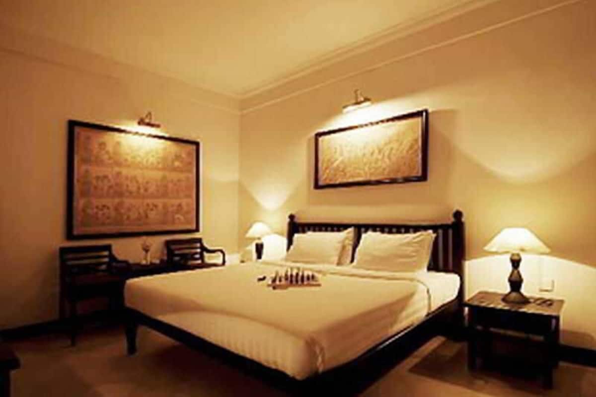 A hotel room with a large bed, two bedside tables, and two wall-mounted lamps.