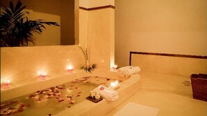 A spa room with a bathtub, candles, and towels.