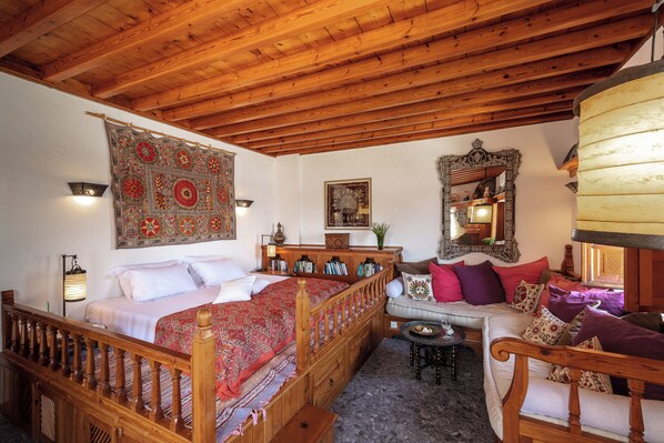 Una habitación tradicional con una cama de madera, un sofá y una mesa de comedor.