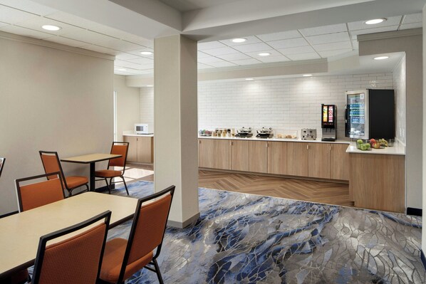 Una habitación de hotel moderna con comedor, kitchenette y un amplio suelo con diseño de mármol.