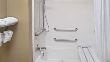 A bathroom with a bathtub, two handrails, a showerhead, and a towel rack with towels.