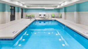 Una piscina con borde de azulejos, un vestuario con banco y una zona de duchas con puerta de cristal.
