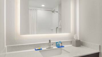 A bathroom with a white sink, a mirror, and a shower.
