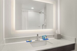 Un baño con lavamanos blanco, un espejo y una ducha.
