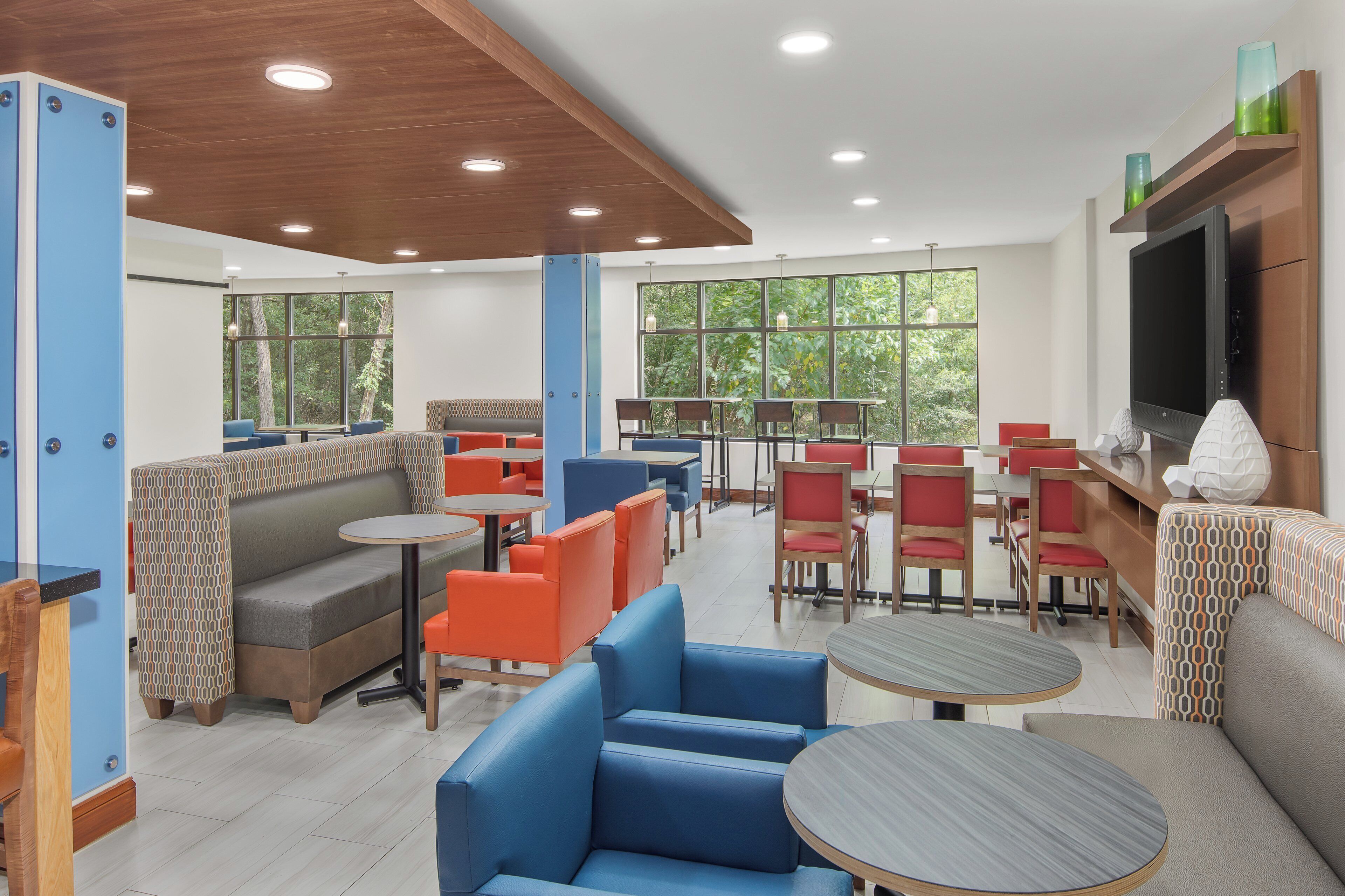 A modern interior with seating arrangements, tables, and a television screen.