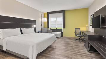 A hotel room with a bed, desk, chair, TV, and a window with a view.
