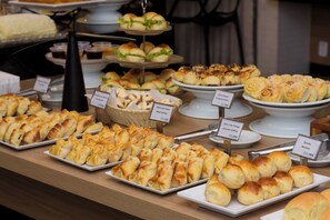 A buffet with various pastries and sandwiches.
