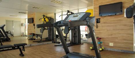 A gym with treadmills, weight machines, and a mirror wall.