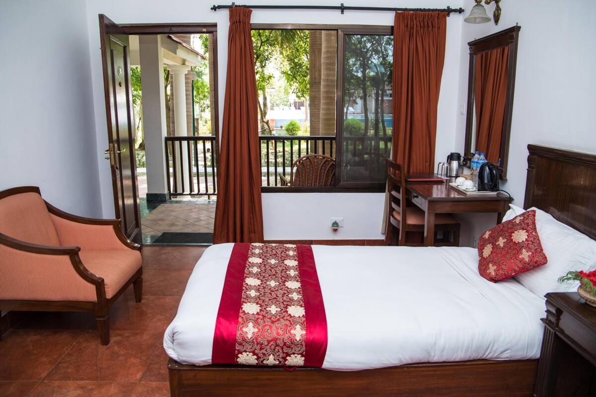 Una habitación de hotel con cama, una silla, un escritorio y vistas al exterior.