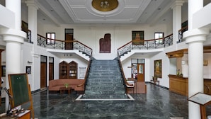 Un vestíbulo espacioso con una escalera de mármol, muebles de madera y una estatua de Buda.