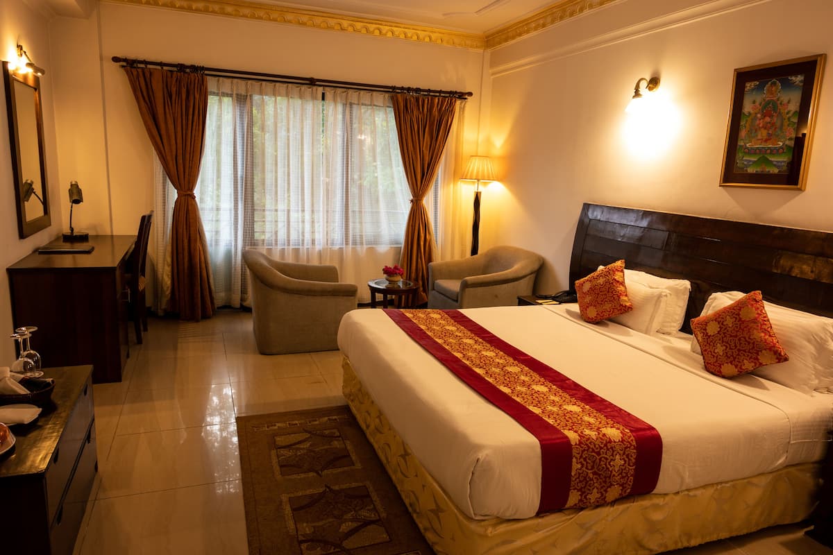 Una habitación de hotel con una cama grande, dos sillones, un escritorio y una lámpara.