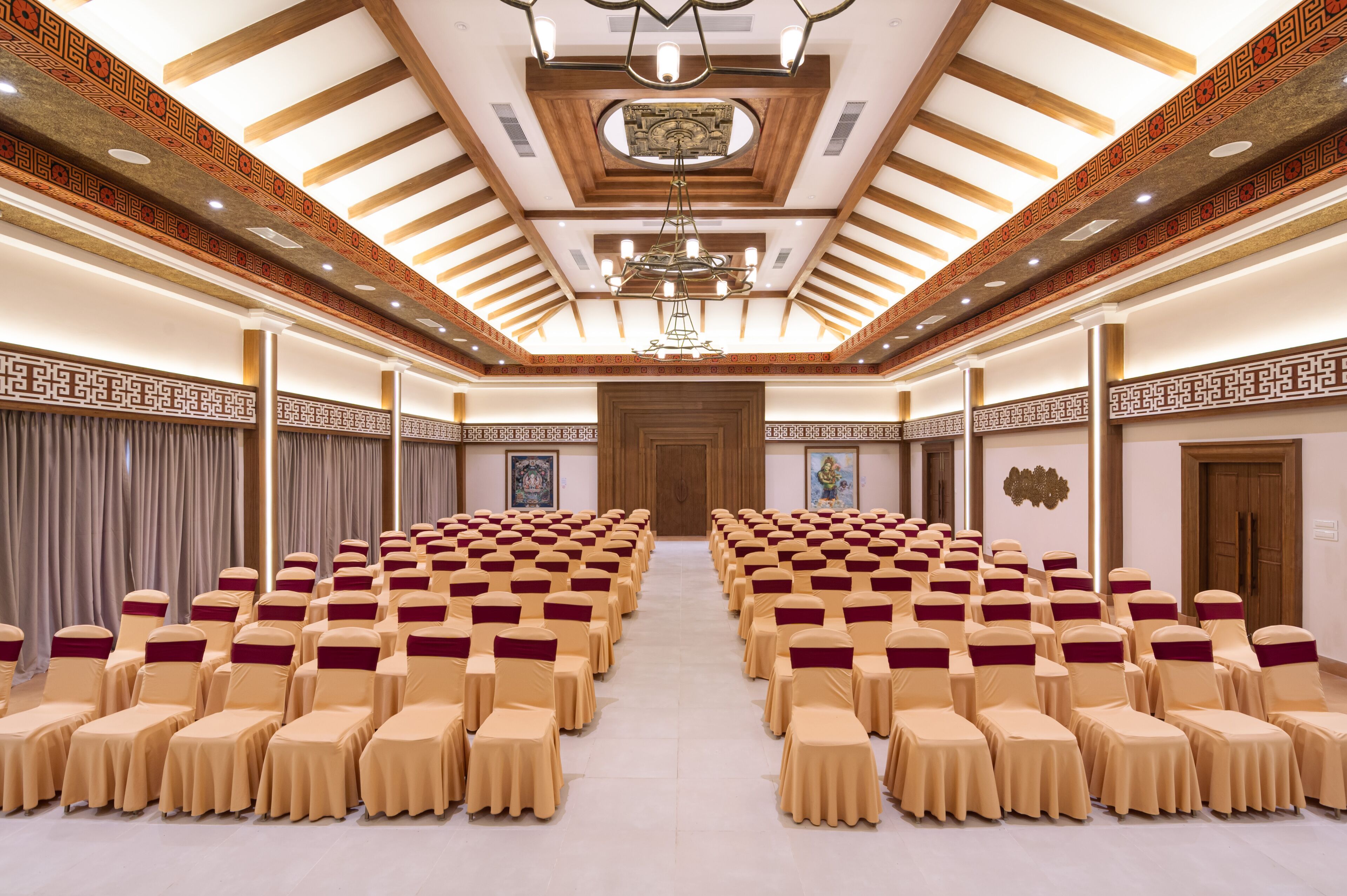 Un salón de conferencias con filas de sillas, una araña y diseños decorativos en las paredes.