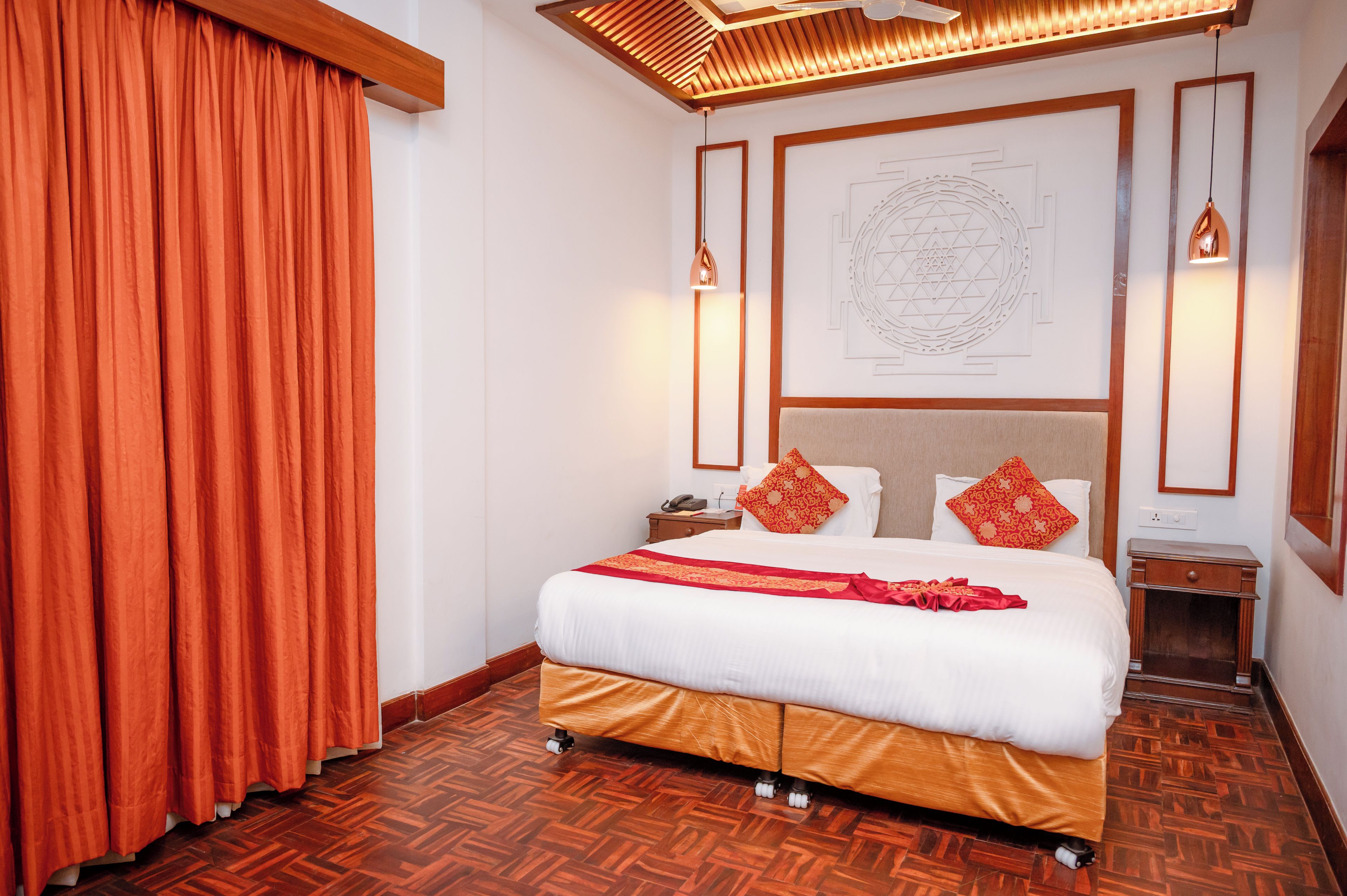A hotel room with a large bed, wooden floor, and a ceiling with a slatted design.