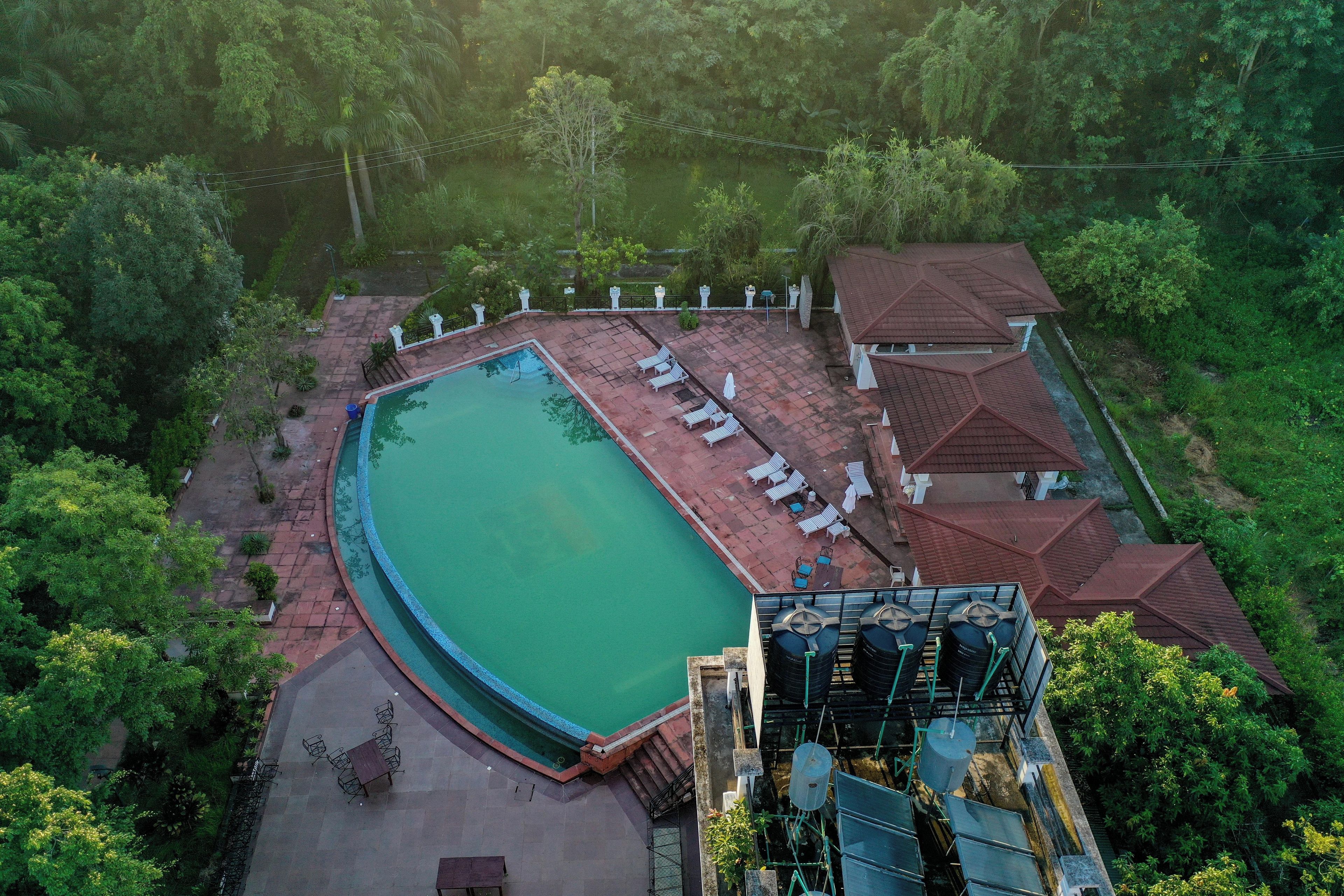 An aerial view of a swimming pool area with lounge chairs and a building with a red roof.