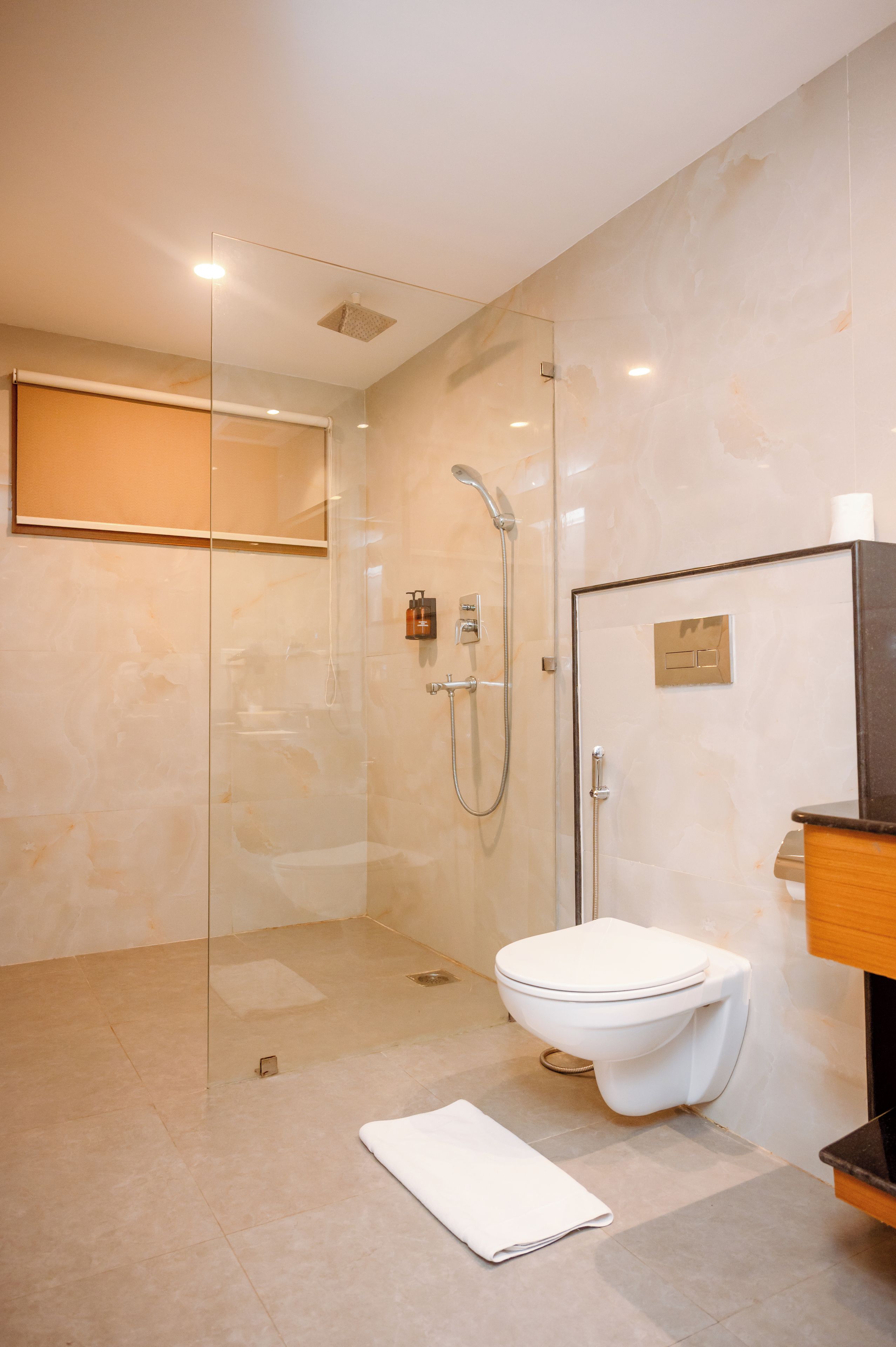 A modern bathroom with a glass-enclosed shower, a toilet, and a wooden vanity.