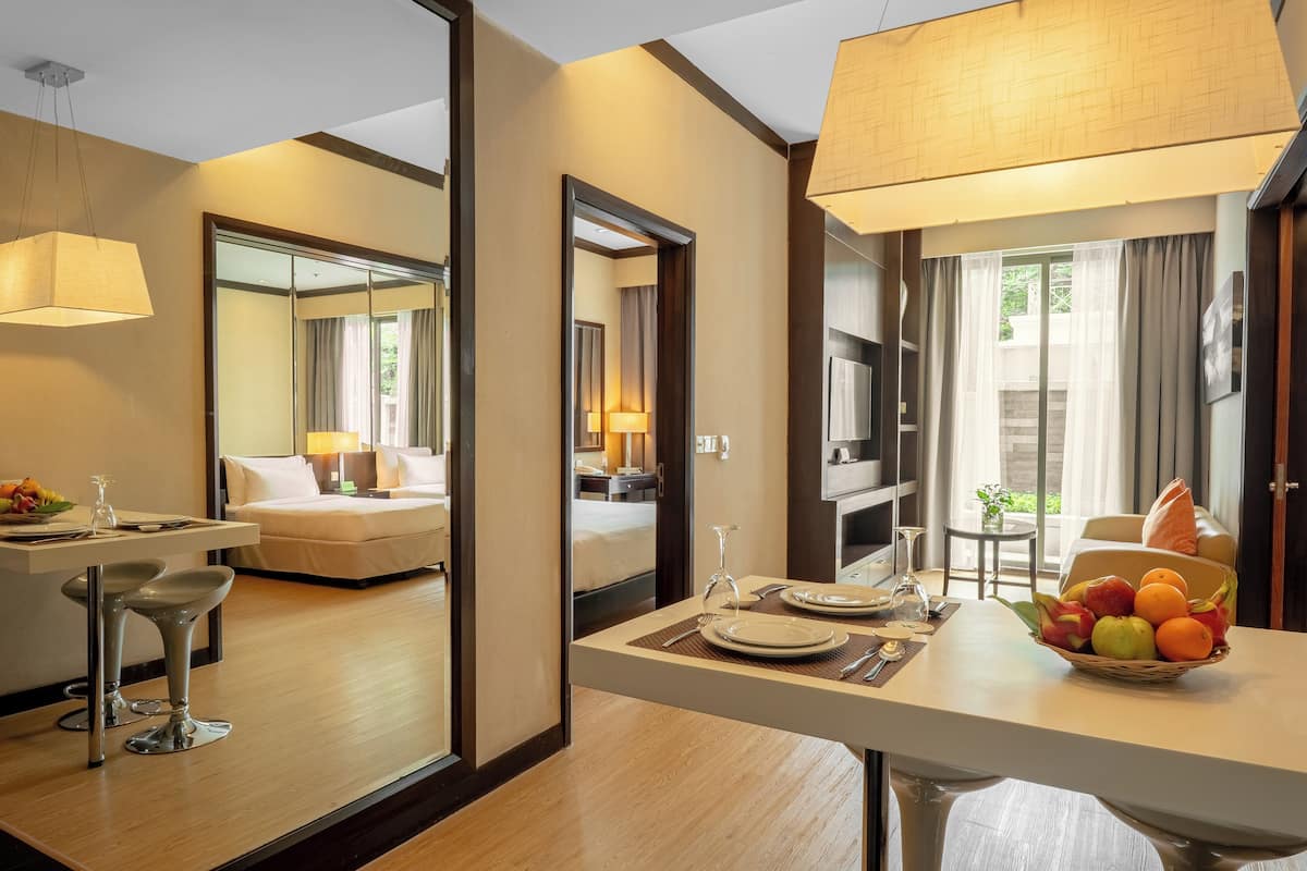 A hotel room with a dining area, a bed, and a large mirror.